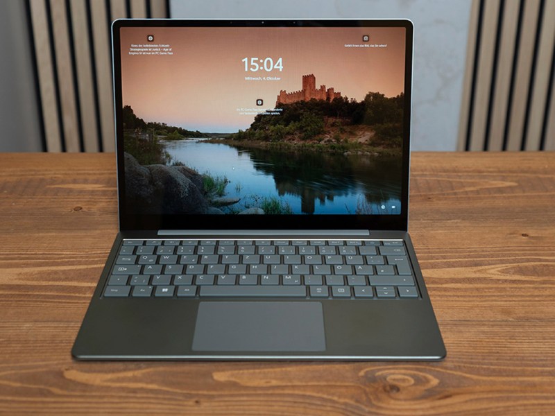 Das Micrsoft Surface Laptop Go 3 liehgt aufgeklappt auf einem Holztisch.