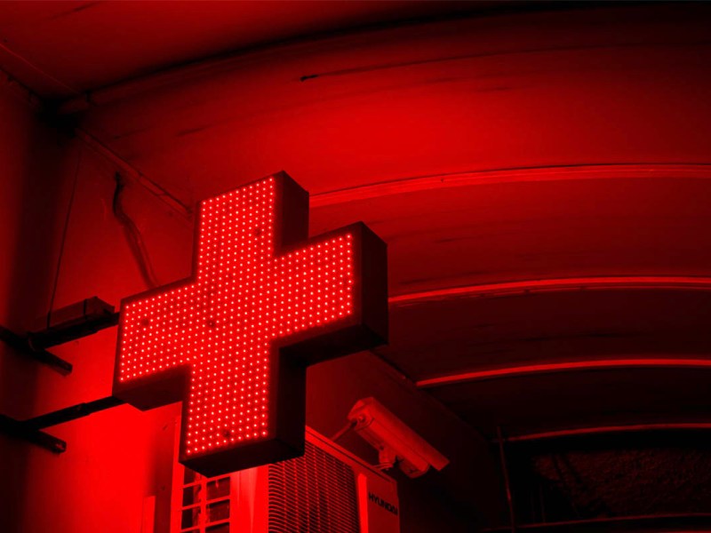Ein leuchtendes Schild, dass einen rotes Kreuz als Rettungsdienst-Zeichen zeigt
