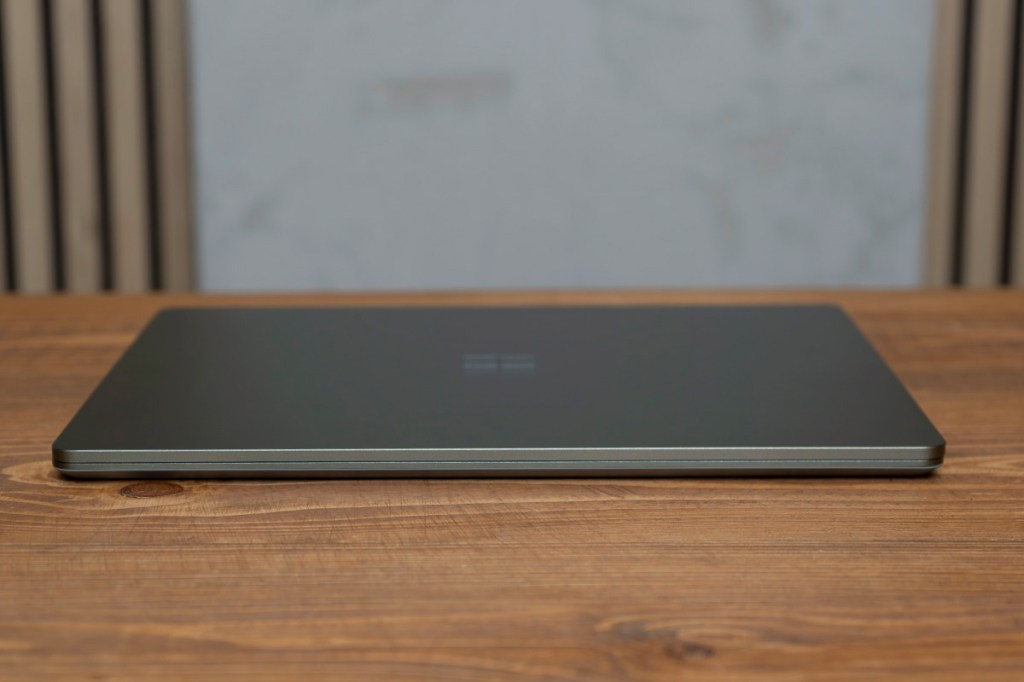 Das Microsoft Surface Laptop Go 3 liegt geschlossen auf einem Holztisch.