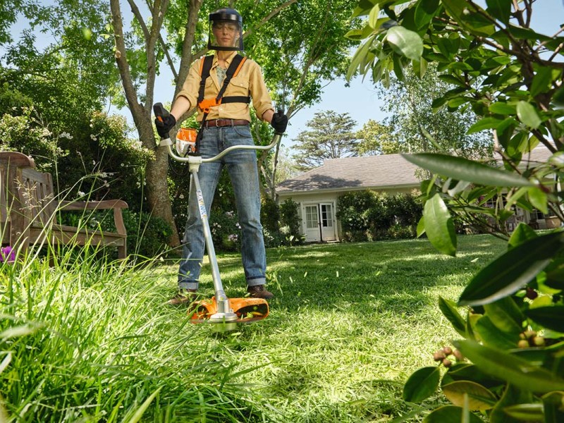 Ein Mann benutzt im Garten eine Akku-Sense