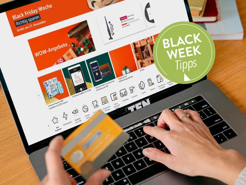 Person an einem Laptop mit Bankkarte in der Hand.
