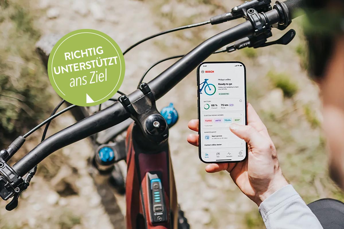 Person mit Smartphone auf einem E-Bike.