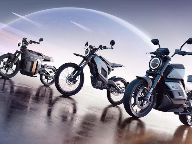 Drei E-Motorräder nebeneinander, dahinter ein graphischer Hintergrund