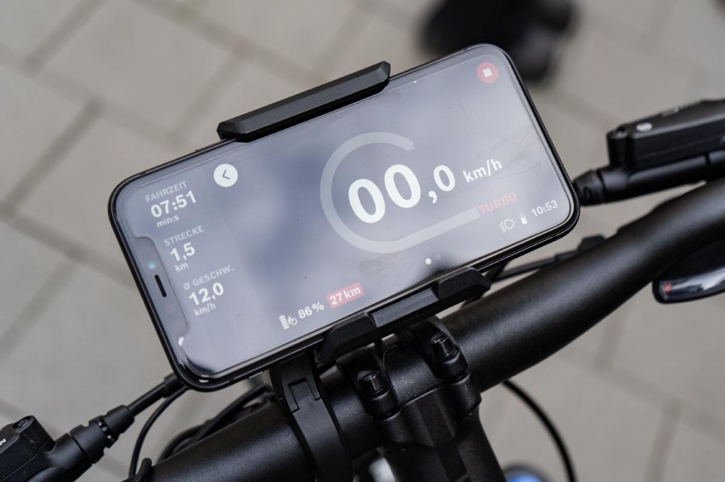 Nahaufnahme: Hand hält Smartphone fest, darauf sieht man Bosch eBike Flow App geöffnet