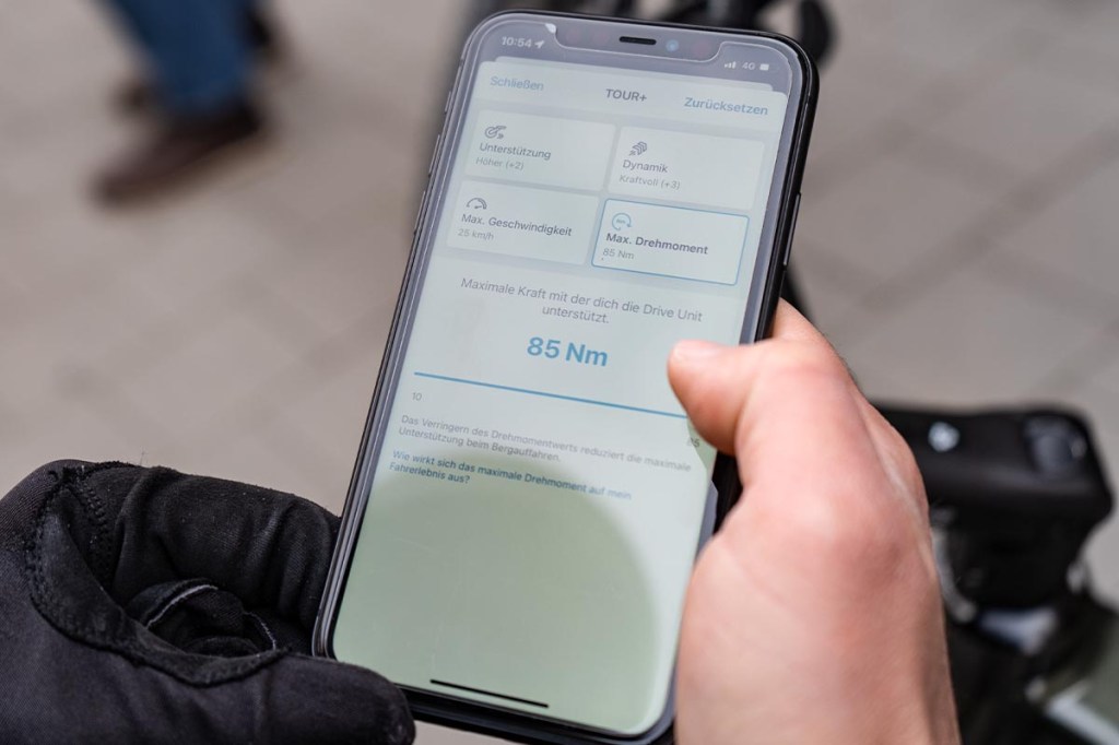 Nahaufnahme: Hand hält Smartphone fest, darauf sieht man Bosch eBike Flow App geöffnet
