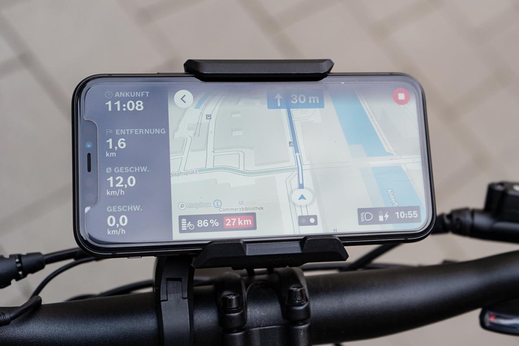 Nahaufnahme: Hand hält Smartphone fest, darauf sieht man Bosch eBike Flow App geöffnet