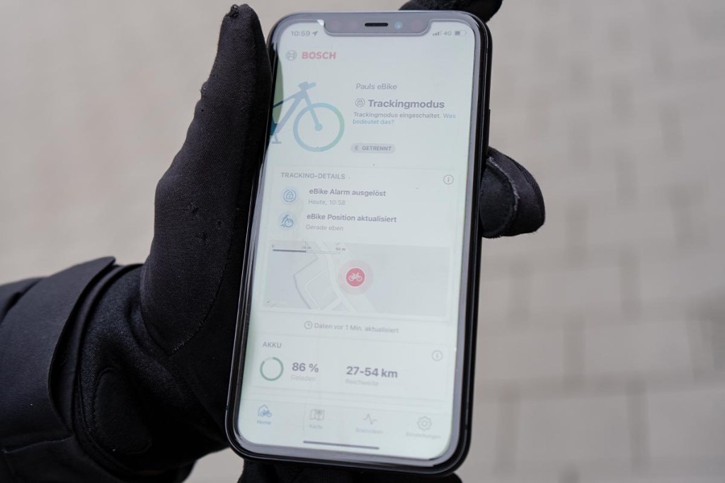 Nahaufnahme: Hand hält Smartphone fest, darauf sieht man Bosch eBike Flow App geöffnet