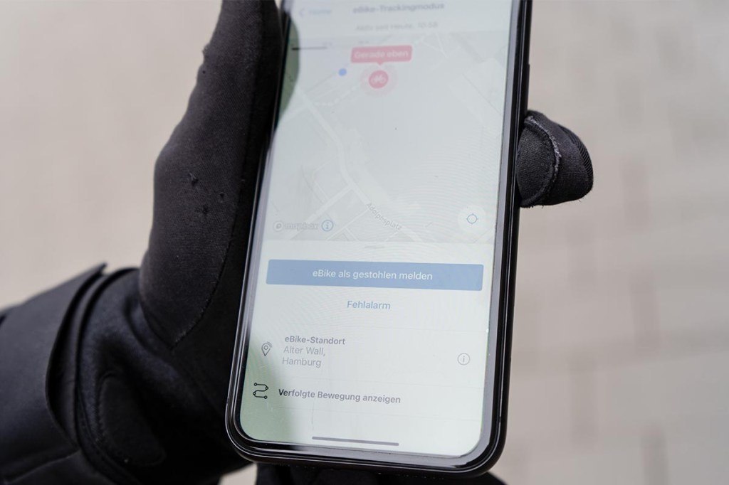 Nahaufnahme: Hand hält Smartphone fest, darauf sieht man Bosch eBike Flow App geöffnet