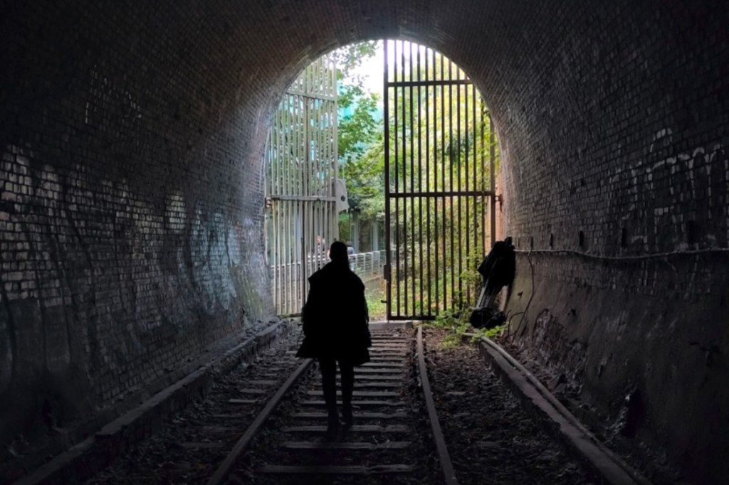 Ein Foto von einem dunklen Tunnel, in der Mitte ist eine Frau zu sehen.