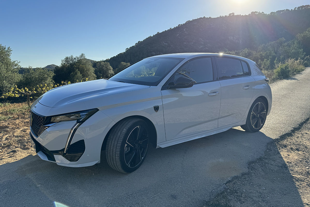 E-Auto Peugeot E-308 im Sonnenlicht vor Bergkulisse.