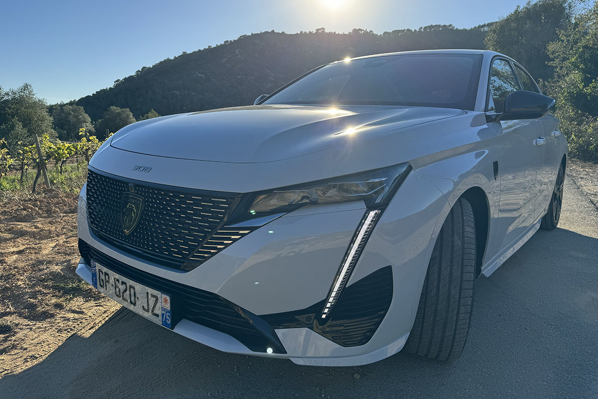 E-Auto Peugeot E-308 von außen vor Meeresprommenade fotografiert – mit Detailansicht des rechten Vorderlichts.