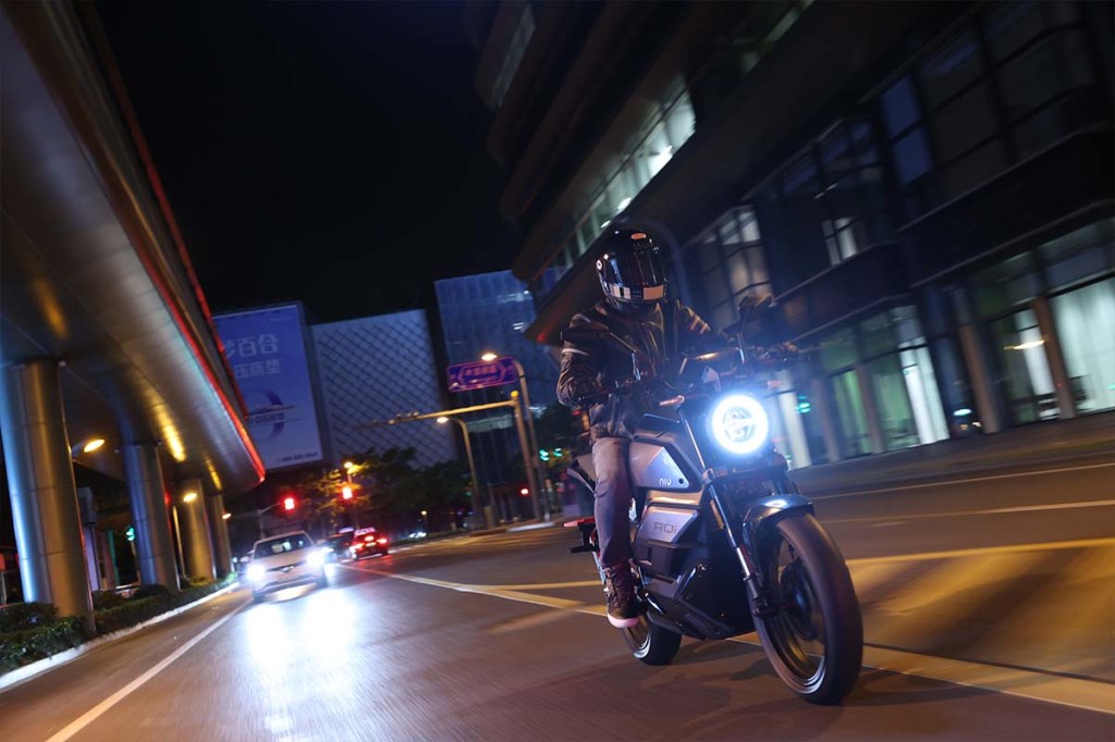 E-Motorrad fährt durch die nächtliche Stadt