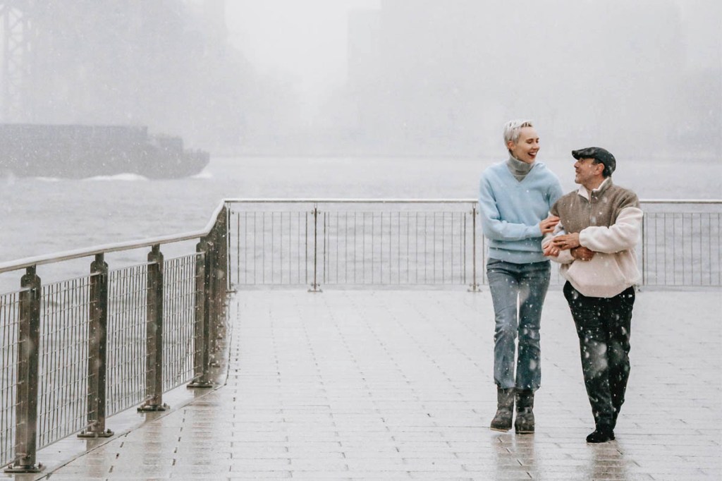 Zwei Menschen gehen im Nebel am Hafen spazieren und lachen.