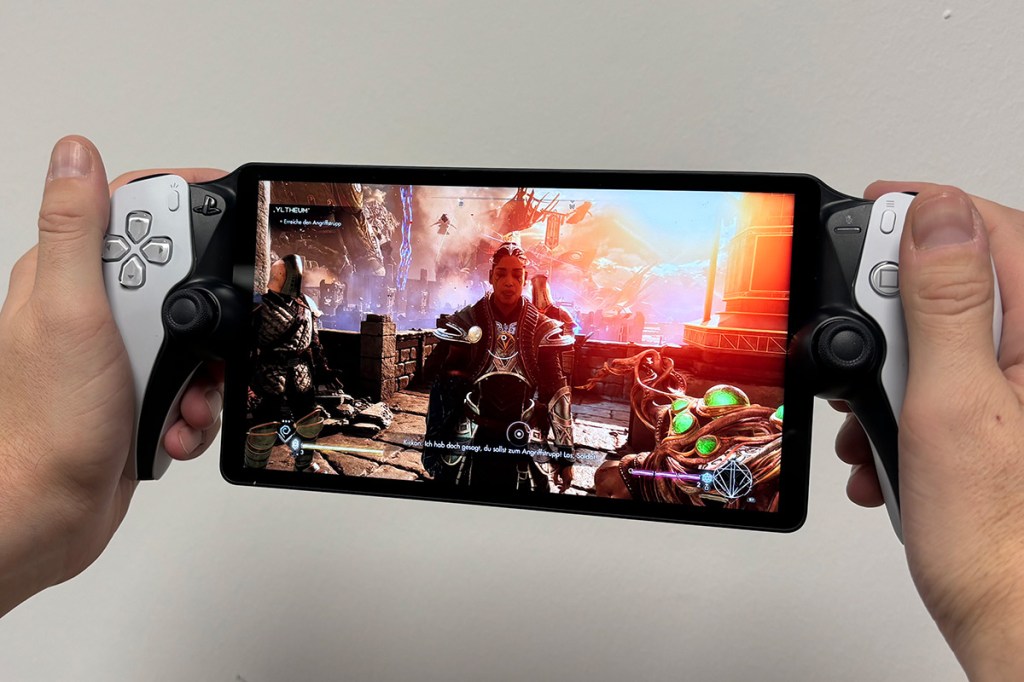 Das PS5-Handheld PlayStation Portal Remote Player, mit beiden Händen gehalten. Auf dem Bildschirm sieht man ein Videospiel.