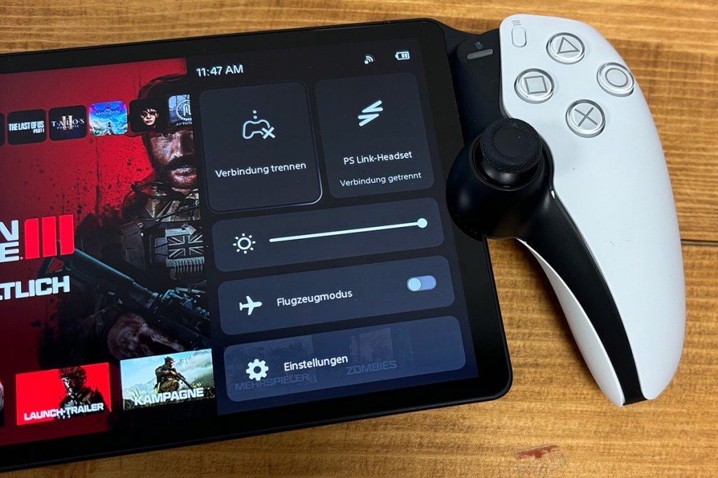 Das PS5-Handheld PlayStation Portal Remote Player, auf einem Holztisch liegend. Auf dem Bildschirm sieht man das Options-Menü.
