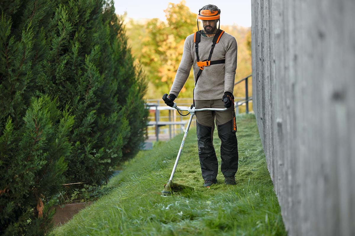 Ein Mann benutzt eine elektrische Sense um Gras zu schneiden.
