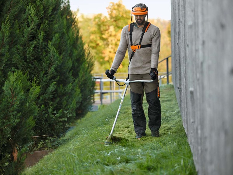 Ein Mann benutzt eine elektrische Sense um Gras zu schneiden.