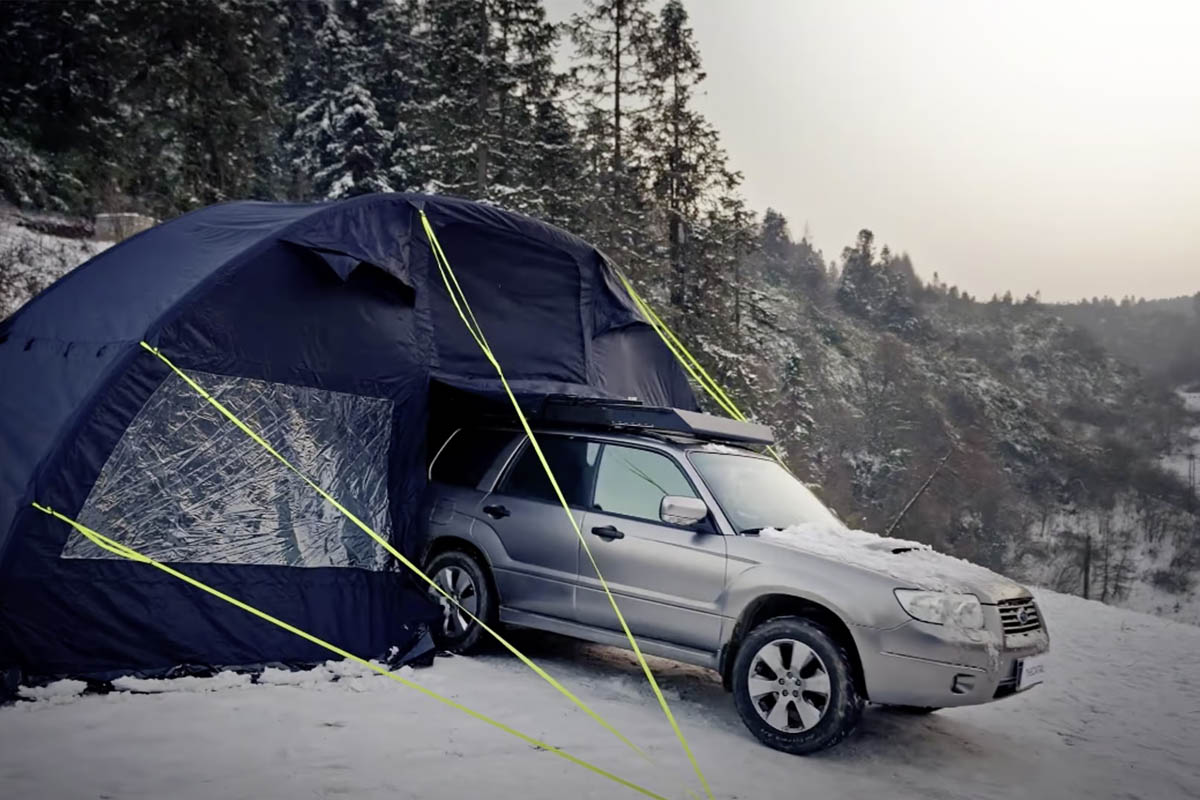 Eine Auto fährt in einer Schneelandschaft aus einem hohen Zelt