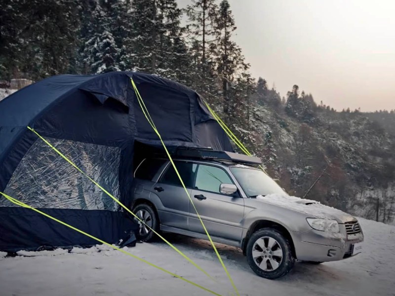Eine Auto fährt in einer Schneelandschaft aus einem hohen Zelt