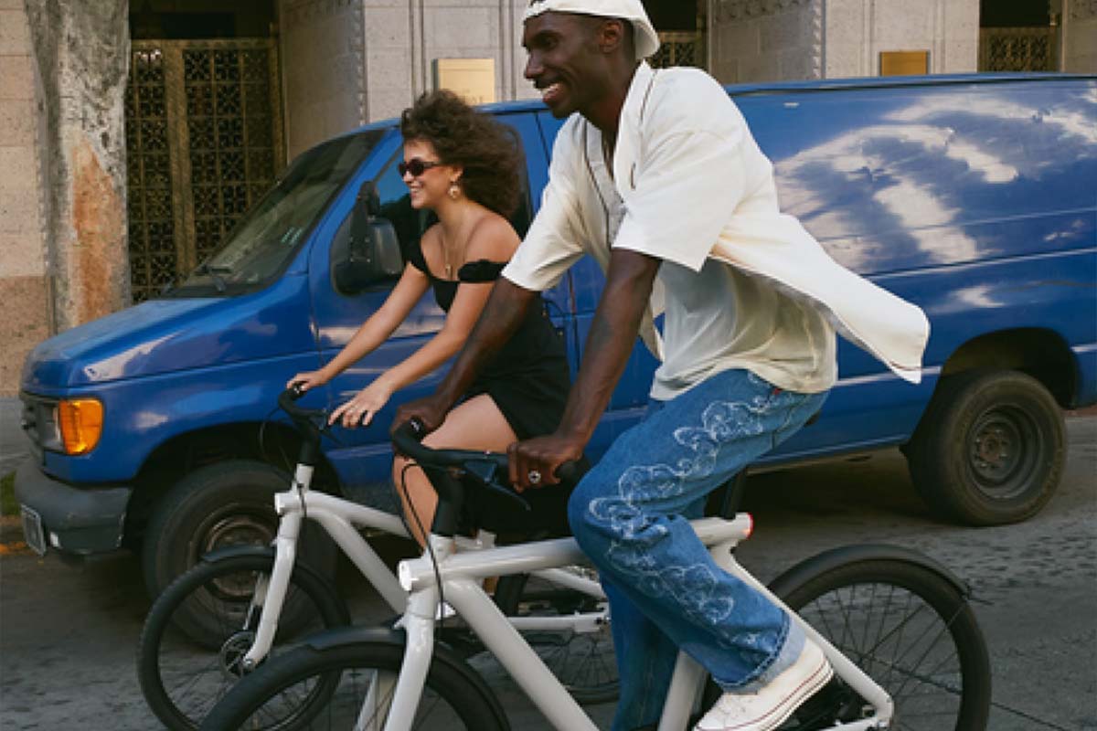Zwei Personen, die offensichlich Spaß haben, fahren mit einem E-Bike durch eine Stadt
