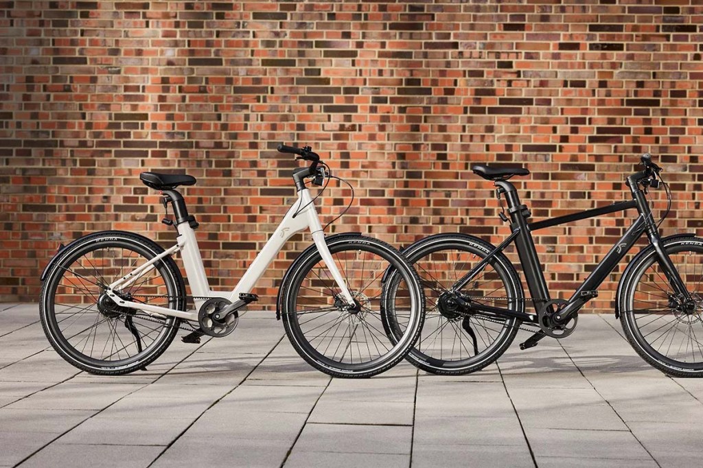 ein weißes und ein schwarzes city-e-bike stehen nebeneinander neben einer mauer