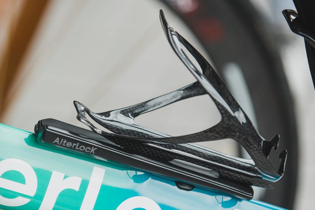 Nahaufnahme von schwarzer Schiene auf türkiser Rahmenstange von Fahrrad mit schwarzer Trinkflaschenhalterung