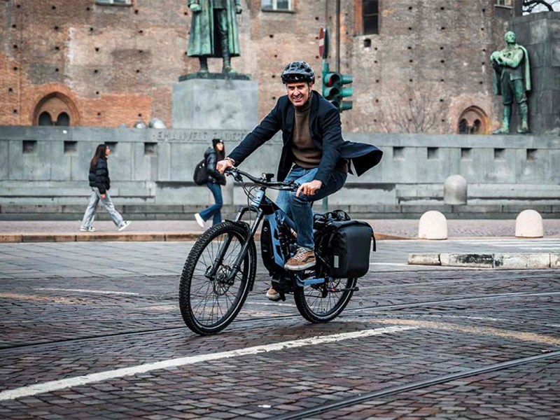 Mann fährt mit einem E-Bike über einen Platz in einer Stadt