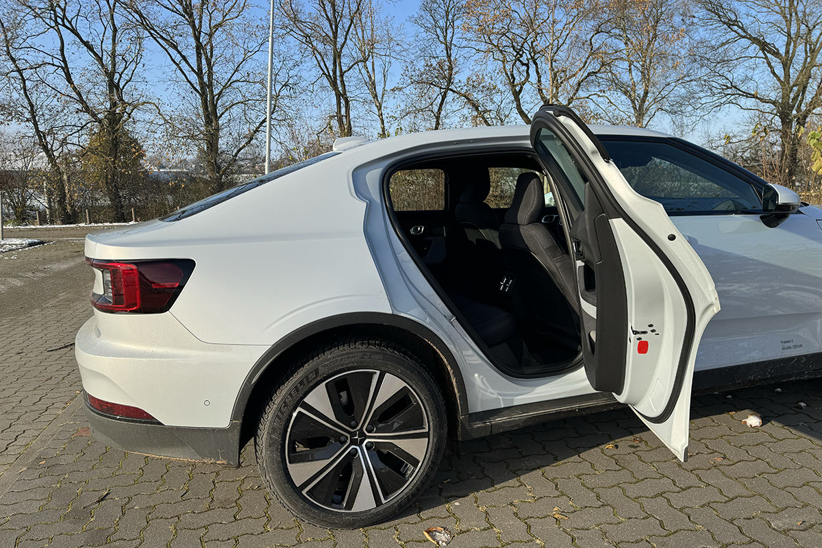 E-Auto Polestar 2 (MY24) Seitenaufnahme auf einem leicht eingeschneiten Parkplatz mit geöffneter rechter Hintertür.