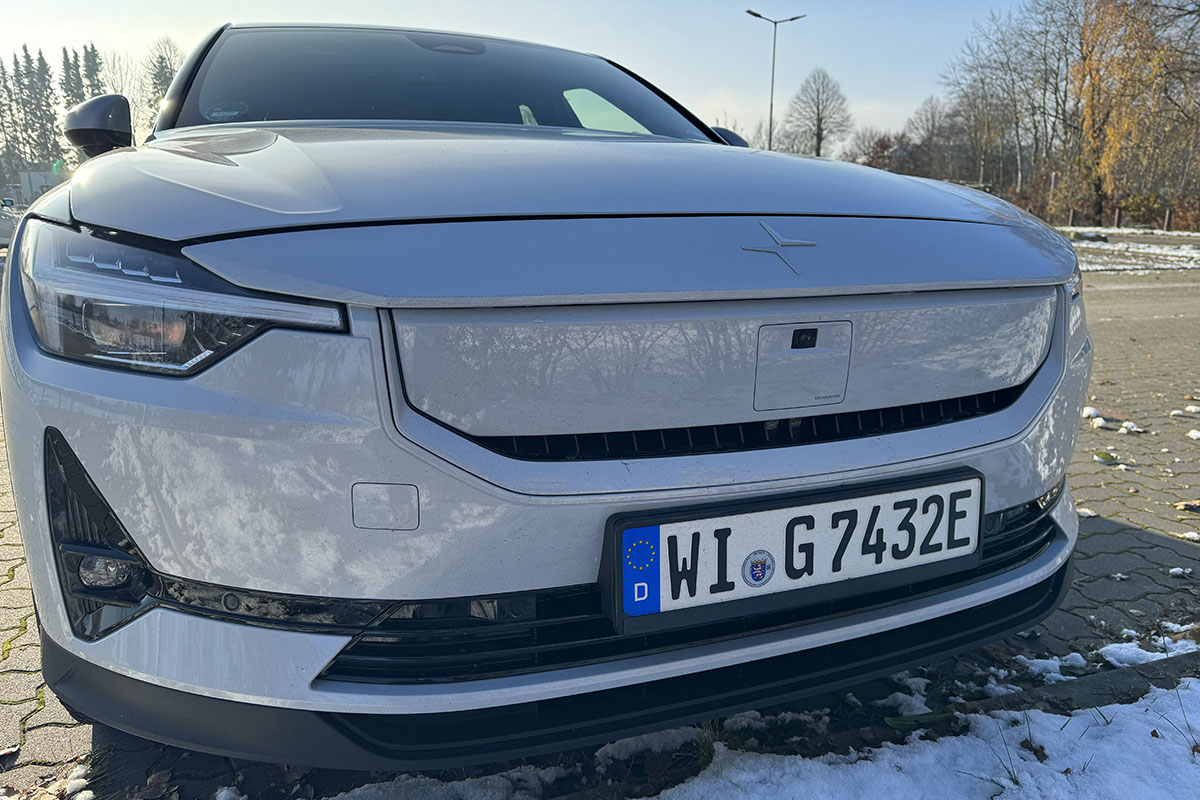 E-Auto Polestar 2 (MY24) Frontalaufnahme auf einem leicht eingeschneiten Parkplatz mit Ansicht der Front.