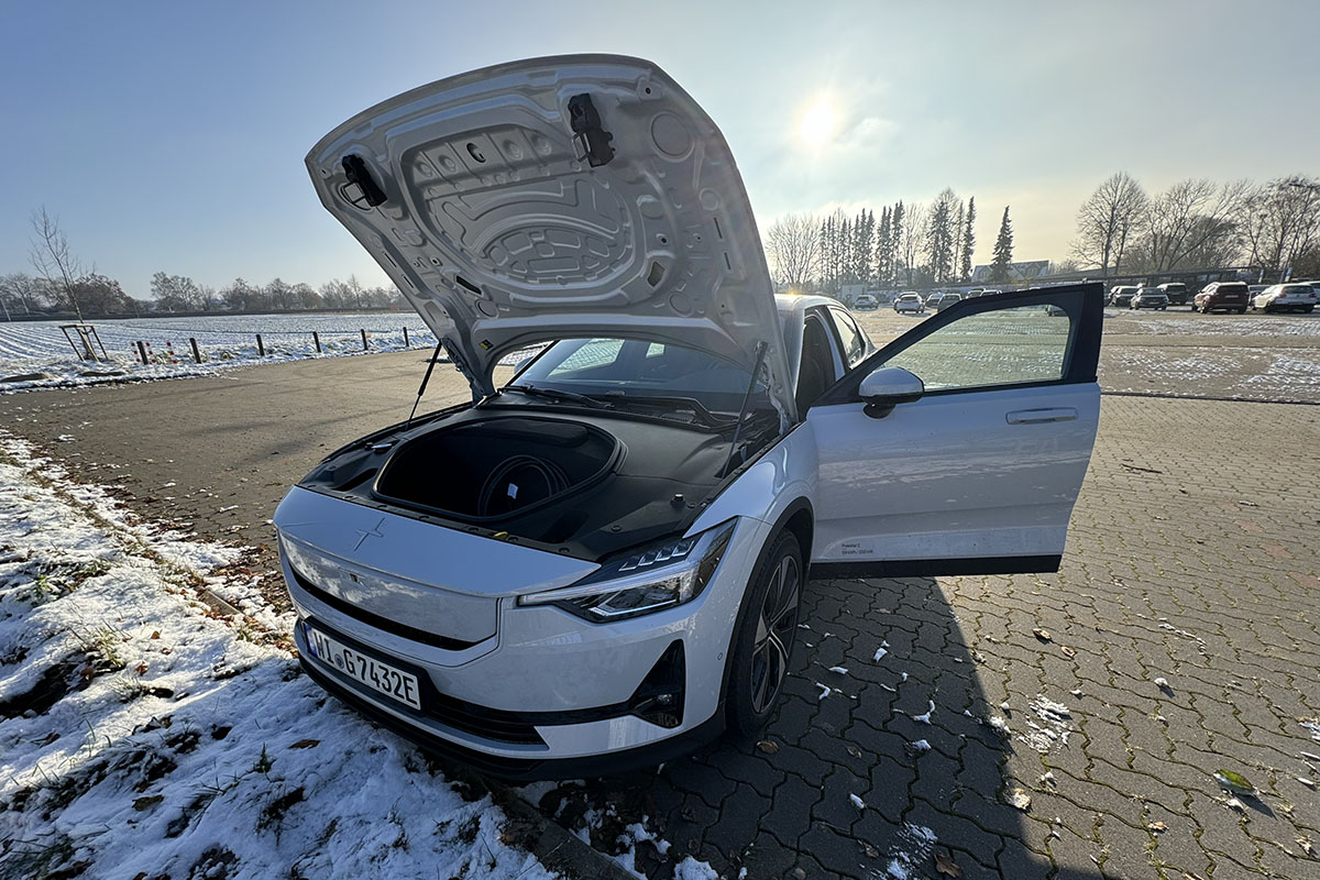 E-Auto Polestar 2 (MY24) auf einem leicht eingeschneiten Parkplatz mit geöffneter Motorohaube.