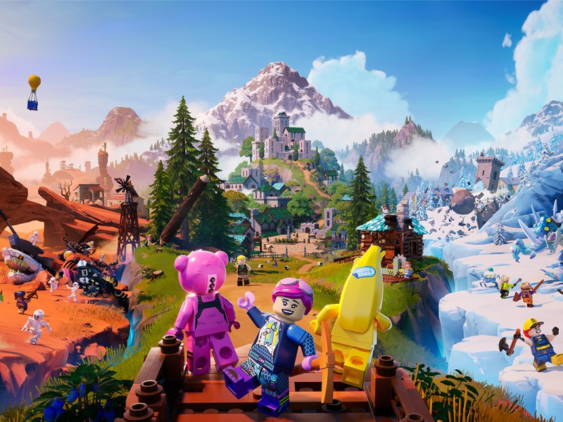 Titelbild von Lego Fortnite. Rechts ein schneebedeckter Berg, links eine Wüste, in der Mitte Grasland. Vorne drei Legofiguren.