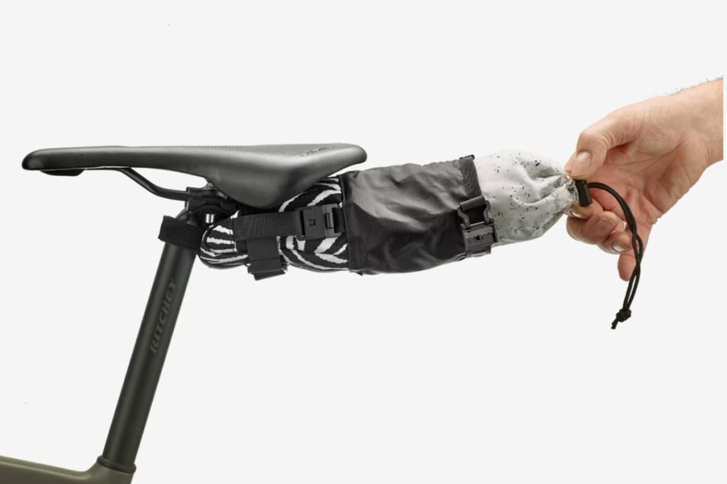 Nahaufnahme Fahrradsattel mit kleiner Satteltasche, eine Hand zieht eine kleine Innentasche aus der Ausßentasche heraus