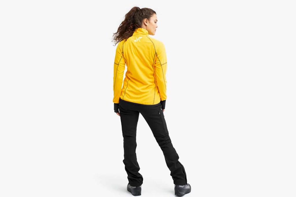 Frau von hinten auf weißen Hintergrund. sie trägt eine gelbe Jacke und eine schwarze Hose