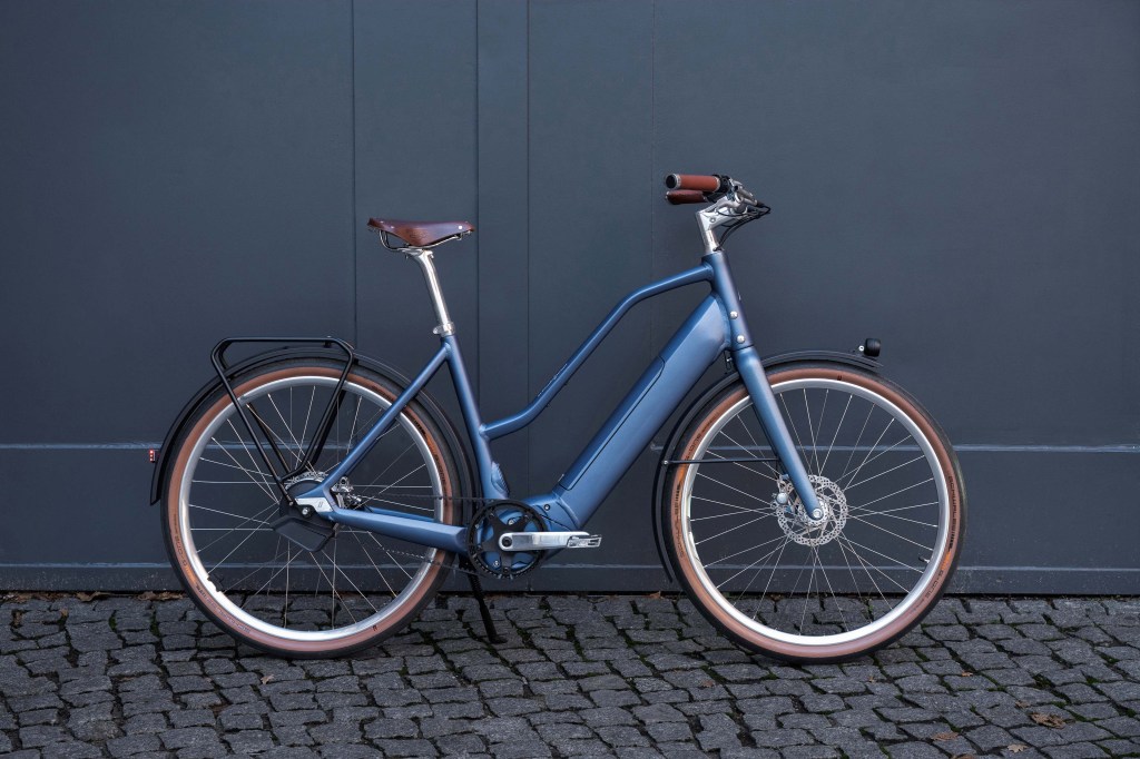 E-Bike von der Seite vor einem blauen Tor stehend