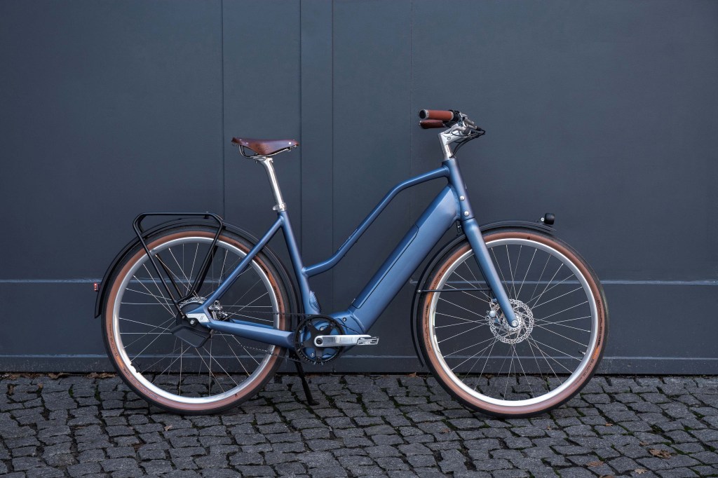 E-Bike von der Seite vor einem blauen Tor stehend