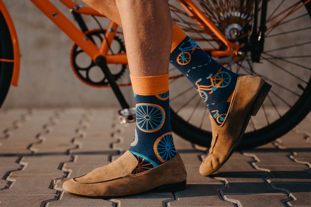 Nahaufnahme: Füße neben einem Fahrrad, Person hat Socken mit Fahrradmuster an