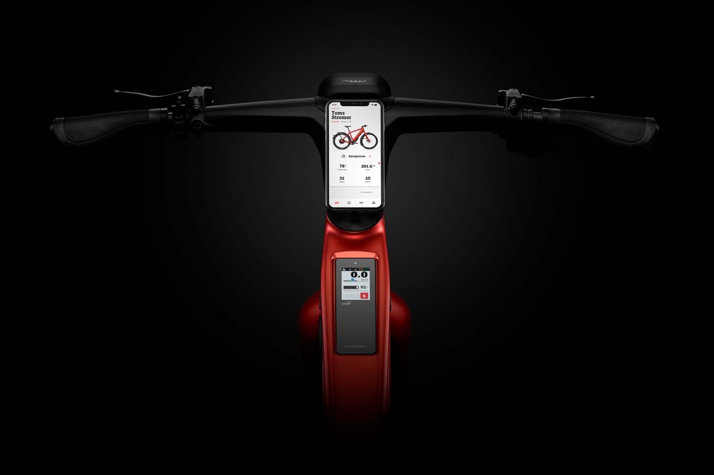 Blick auf den Lenker eines E-Bikes, ein Smartphone ist dort mittig als Display befestigt, schwarzer Hintergrund