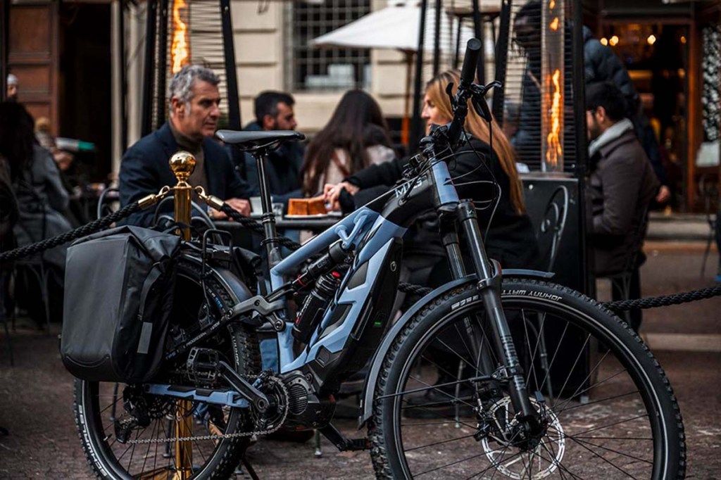 E-Bike vor einem Cafe stehend, im Hintergrund sitzen Personen an Tischen
