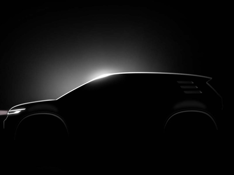 Silhouette eines Autos, die man nur sieht, weil auf die Windschutzscheibe ein Lichtspot gerichtet ist, schwarzer Hintergrund
