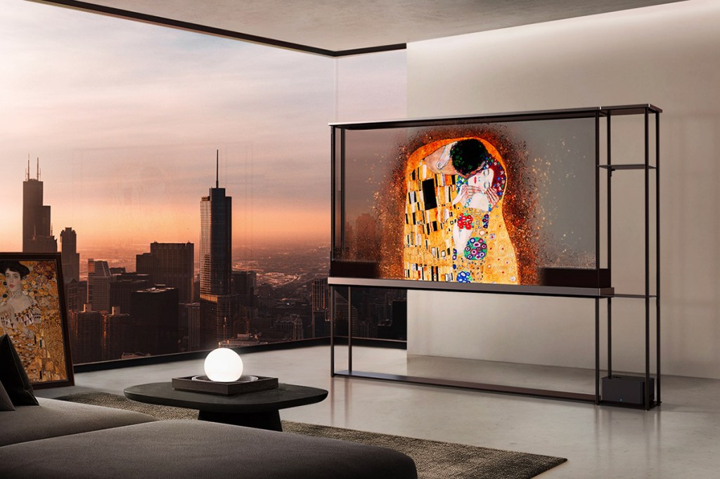 Bild vom transparenten TV LG OLED T, in einem Loft stehend, mit Klimts Kuss auf dem Display und Skyline durchs Fenster im Hintergrund.