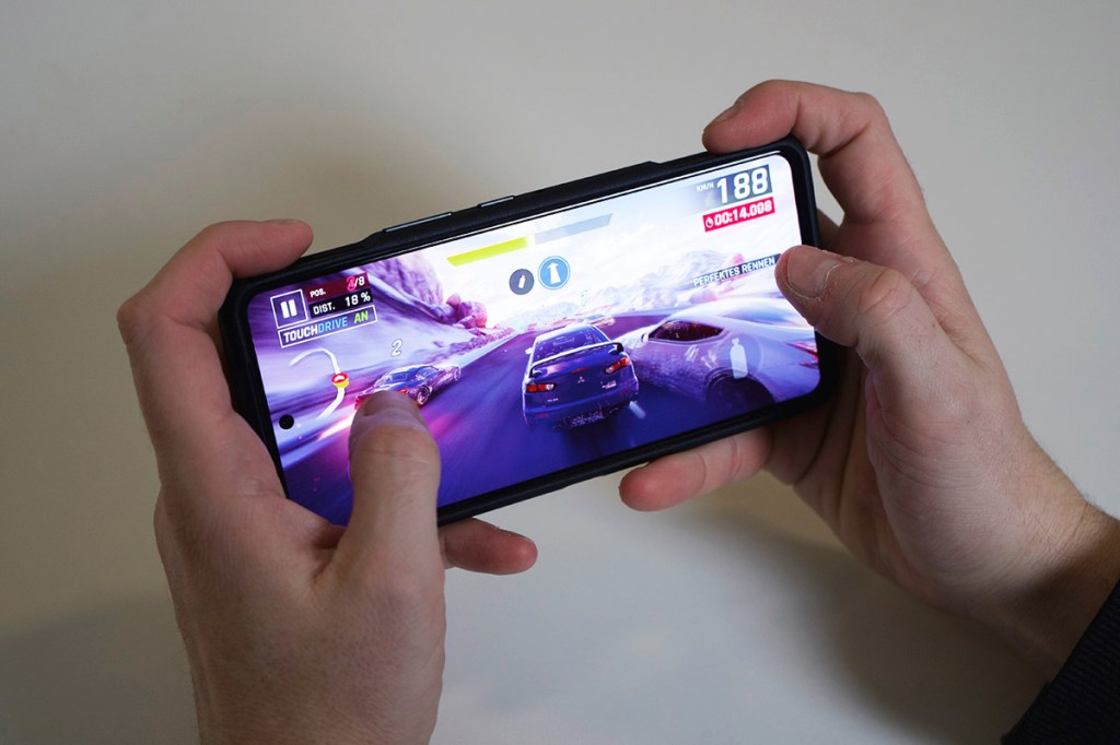 Eine person spielt ein Rennspiel auf dem ASUS ROG Phone 8 Pro.
