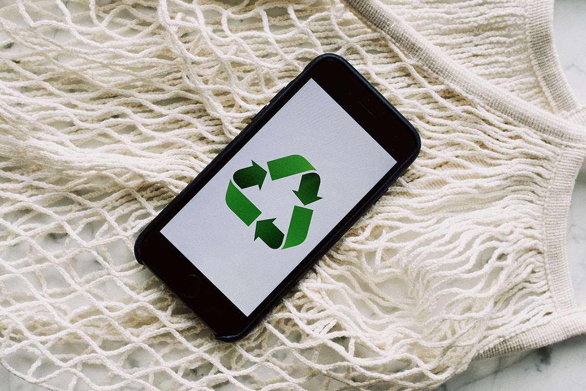 Ein recycltes Smartphone auf hellen Stofffäden liegend.