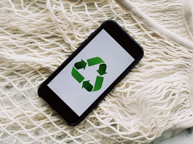 Ein recycltes Smartphone auf hellen Stofffäden liegend.