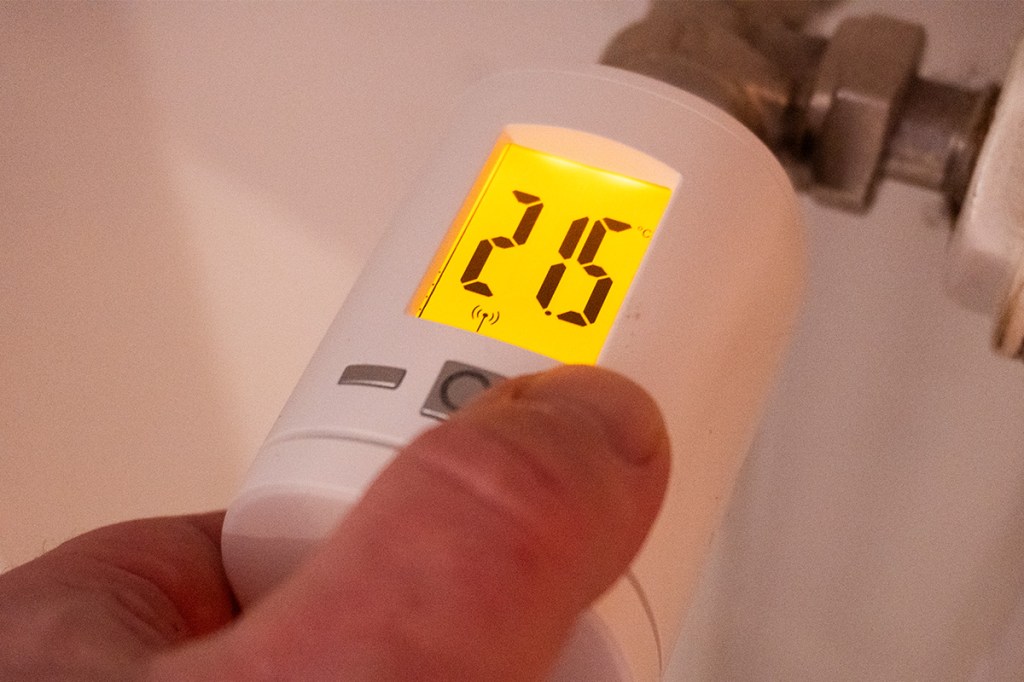 Eine Hand stellt die Temperatur am Homepilot Heiszkörperthermostat ein.