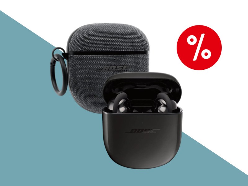 Schwarze Bose Quietcomfort Earbuds II Kopfhörer in schwarzem geöffnetem Ladecase hinter dem eine graue Tasche für das Ladecase ist vor weiß dunkeltürkisem Hintergrund mit rotem Prozentbutton oben rechts