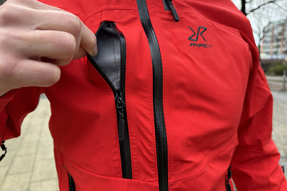 Detailbild zeigt, wie ein wie eine Brusttasche bei einer Regenjacke geöffnet wird.