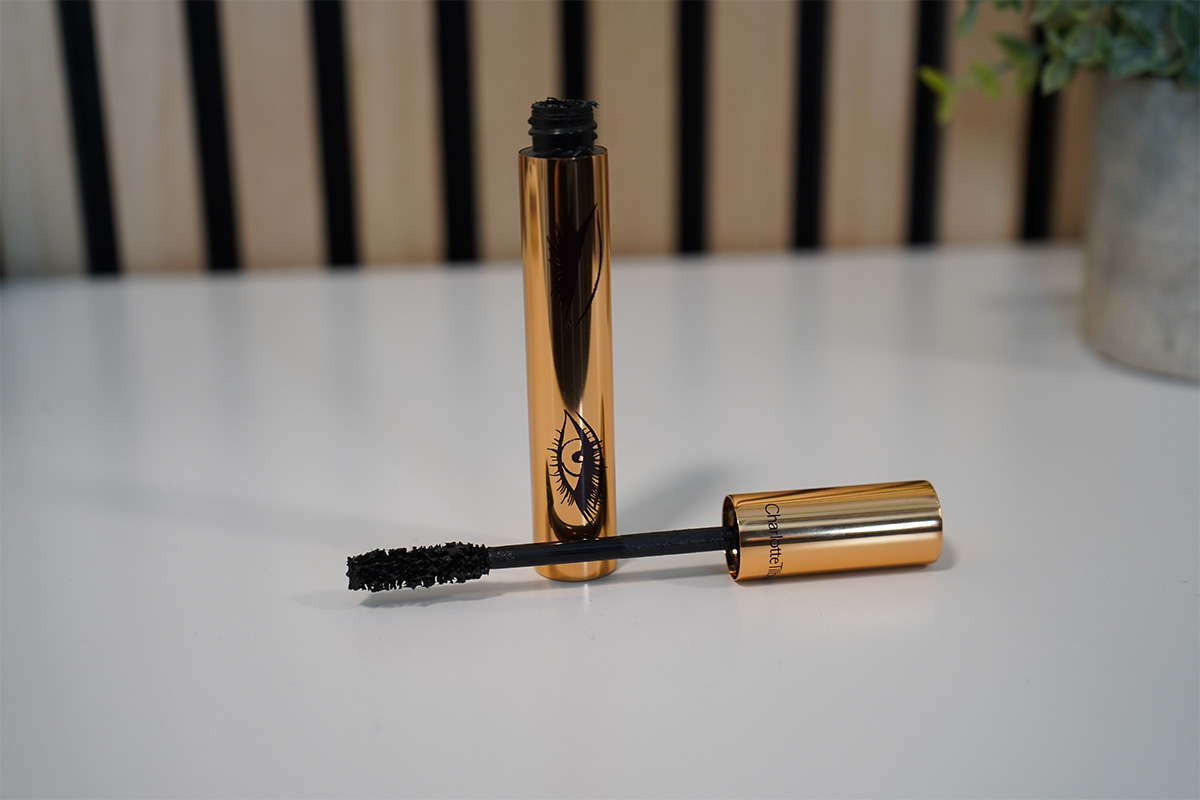 Der Mascara von Charlotte Tilbury auf einer weißer Tischplatte. Der Applikator liegt quer vor dem Wimperntusche-Behälter.