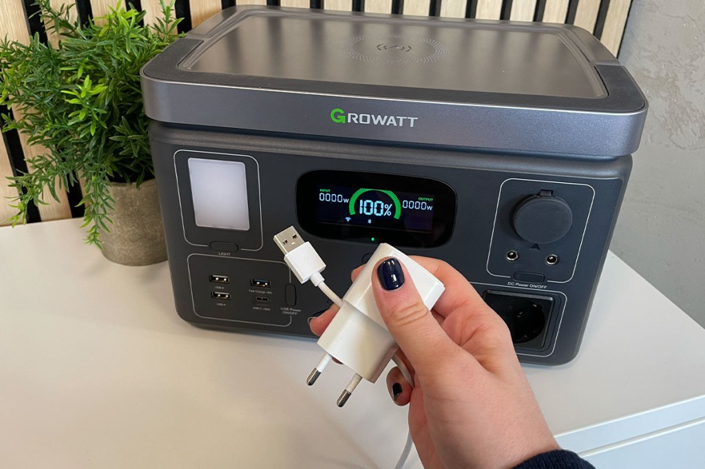Ein USB-Kabel und ein Netteil werden vor die Growatt Vita 550 gehalten.