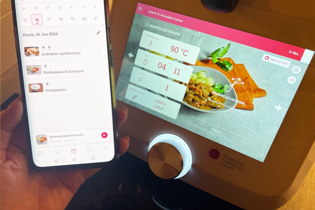 Ein Handydisplay mit der geöffneten Monsieur-Cuisine-App neben dem Display des Geräts.