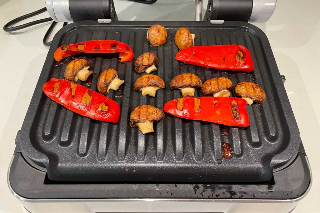 Gegrillte, rote Paprika und Champignons auf der Grillfläche des Optigrill 4in1 von Tefal.